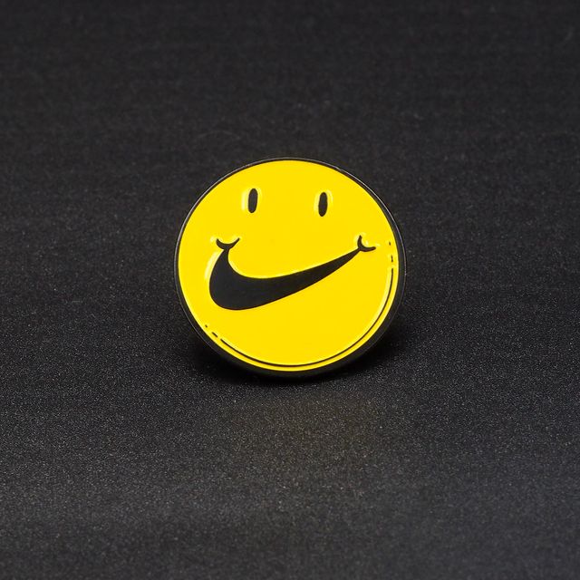 Nike Smile Pins, Smiley met Nike Swoosh als Mond, geel met zwarte speld 